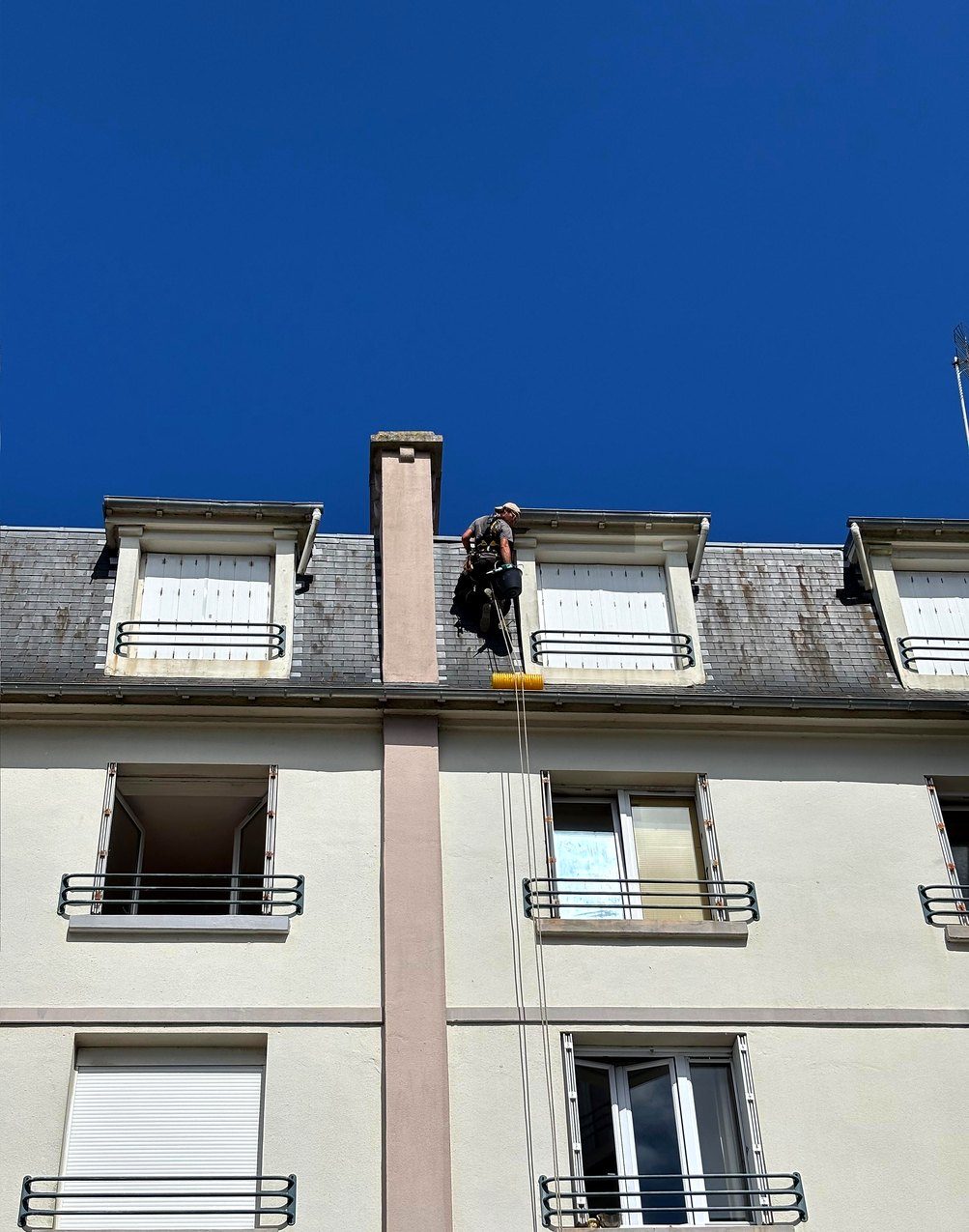 Cordiste en descente sur la façade d'un immeuble d'habitation
